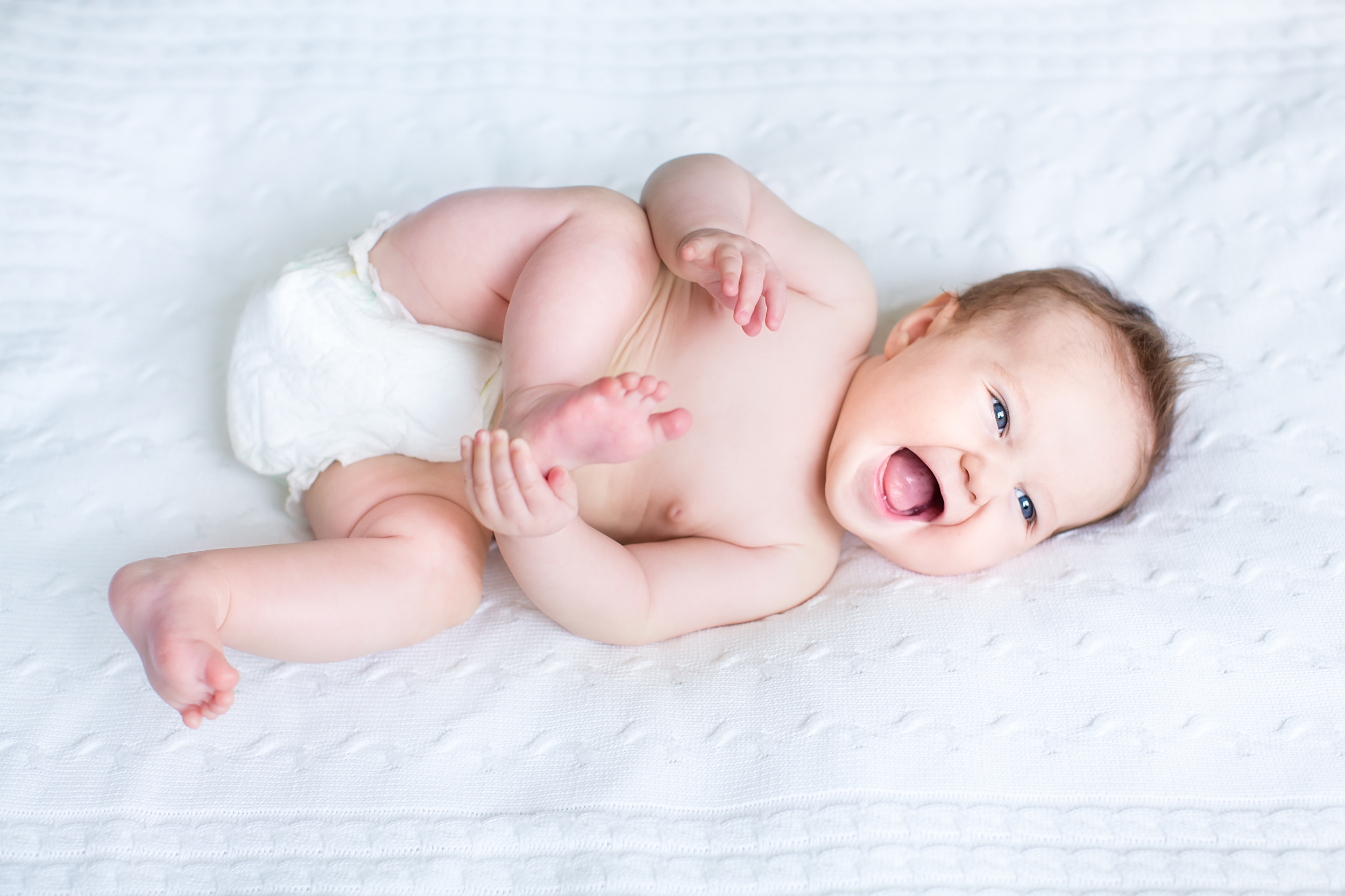 Funny,Laughing,Baby,Wearing,A,Diaper,Playing,With,Her,Feet